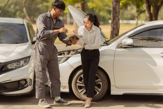 The insurance agent showed the anxious female driver at the scene of the car accident details on his smartphone, emphasizing the claims process to the Asian businesswoman after the collision.