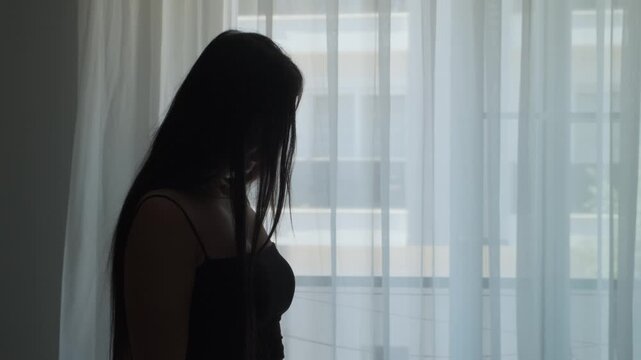 Stressed traveler standing in dark apartment doorway feeling homesick emotionally overwhelmed and exhausted from constant relocation and lonely temporary living, close up silhouette