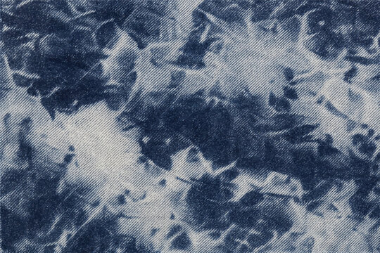Acid wash dark denim fabric seamless texture with bleach-splashed grunge marks, faded indigo and white marble wash effect on authentic cotton denim weave