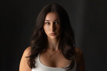 Fototapeta premium Woman looking at camera in a studio setting with a dark backdrop