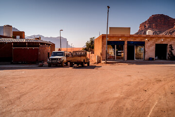 Old pickup trucks in Wadi Rum village against backdrop desert landscape with majestic mountains, Jordan. © Tomasz