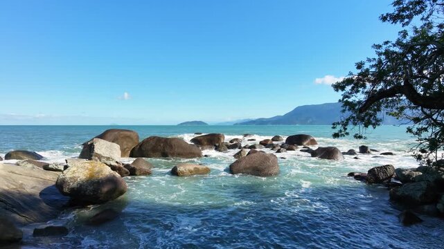 Tropical beach with waves hitting on the rocks at Brazil