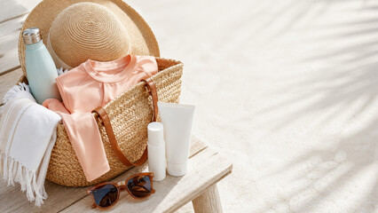 Summer beach essentials on wooden table, featuring straw hat and sunscreen © dvoevnore