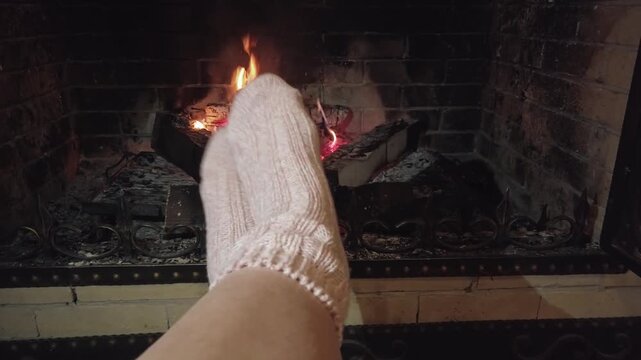 Comfortable knitted socks resting by a blazing fireplace evoke warmth and relaxation