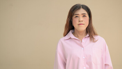 Fototapeta premium Portrait of a transgender Thai Isan businesswoman standing against a plain background