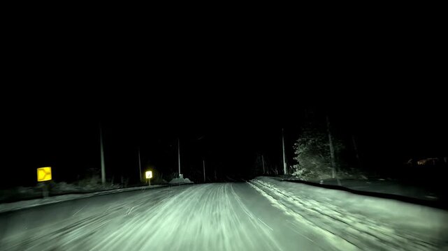 A fast-moving car on a snowy night drive in the country.