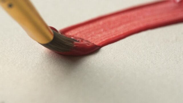 Close-up of brush bristles on paper drawing a red line with paint, oil or gouache, concept of leisure and hobby