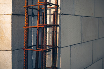 Naklejka premium Construction detail showing steel rebar reinforcement beside lightweight concrete blocks. Architecture, engineering, durability and building industry concept.