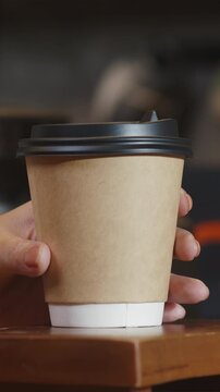Vertical Screen : Young Asia female barista serving take away hot coffee paper cup to consumer standing behind bar counter at cafe restaurant. Owner small business, food and drink, service mind.