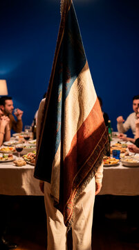 Person hidden behind hanging patterned flag at festive dinner gathering