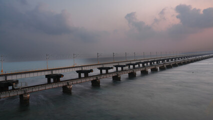 Fototapeta premium A scenic view of Pamban railway bridge over the sea near Rameswaram in Tamil Nadu, India, captured during soft evening light with cloudy sky and calm ocean water.
