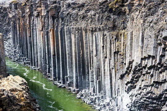 Basalt columns at Studlagil Canyon with green river water in East Iceland