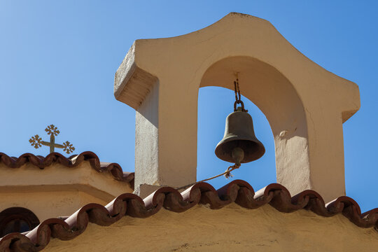Architecture detail of traditional Greek Orthodox chapel of Agios Antonios in the village of Gouves. Rooftop with bell against blue sky. Travel Greece symbol