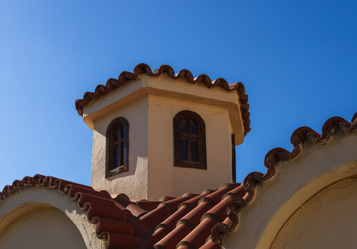 Architecture detail of traditional Greek Orthodox chapel of Agios Antonios in the village of Gouves. Rooftop with main tower against blue sky. Travel Greece symbol