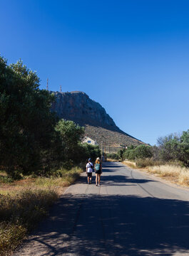 Mother and young son with an arm brace walking on a road towards Gouves village in Crete. Mount Ederi in the background, enjoying a vacation despite medical restrictions