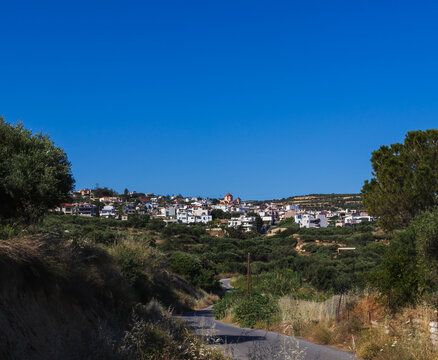 Scenic panoramic view of the traditional hillside village of Gouves in Crete, Greece, featuring the prominent Zoodochos Pigi church in the village center