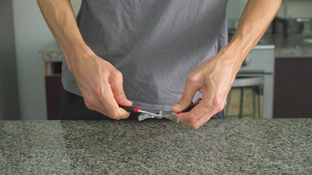 Close up man examining and clicking pliers with clear sound. Hands testing tool at table. Mechanical work, craftsmanship, repair process and satisfying ASMR concept.