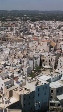 Vertical view of aerial view of Polignano a Mare, panorama of the Lama Monachile beach, waterfront and the buildings of the old town, Puglia, Italy