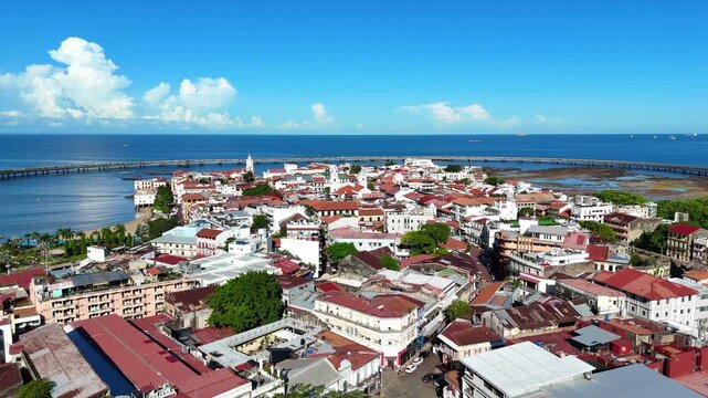 Cinematic aerial drone footage of Casco Viejo, Panama City's historic district. Elevated panoramic view showcasing colonial buildings, churches, colorful rooftops, the coastal seawall, and the Pacific