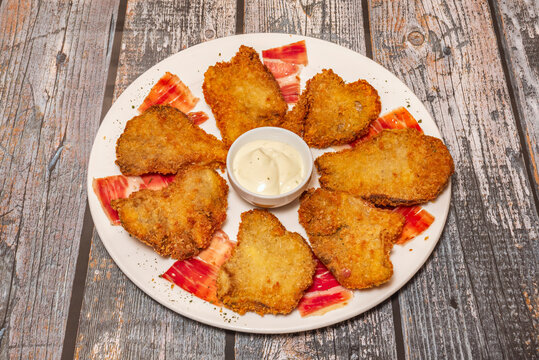 A rustic earthenware bowl holds several portobello mushrooms coated in golden panko breadcrumbs, their interiors juicy and steaming, accompanied by a sprig of fresh rosemary