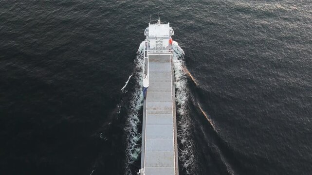 High-angle drone shot capturing the wake and movement of a large cargo vessel.