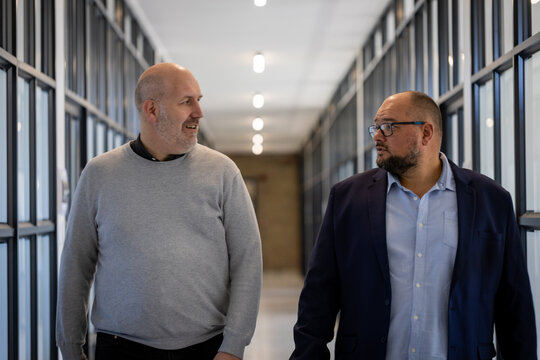 Two businessmen talking while walking through office corridor