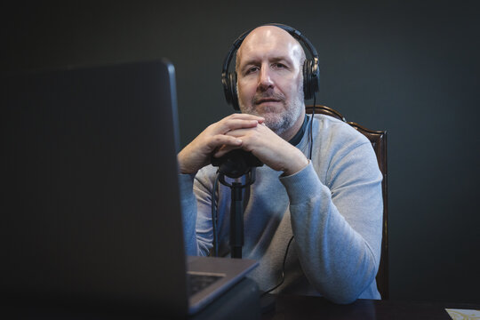 Middle-aged man with headphones and microphone at laptop