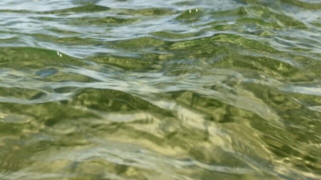 Beautiful sun reflection and light caustics on a sandy bottom through crystal clear turquoise sea water in Kato Gouves, Crete, Greece. Abstract moving water surface background
