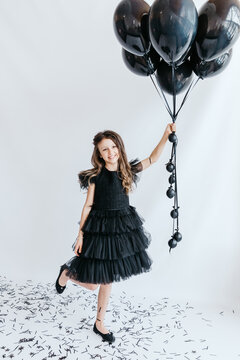 A happy child with black balloons at a holiday photo shoot.
