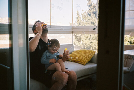Anonymous man with baby blowing soap bubbles