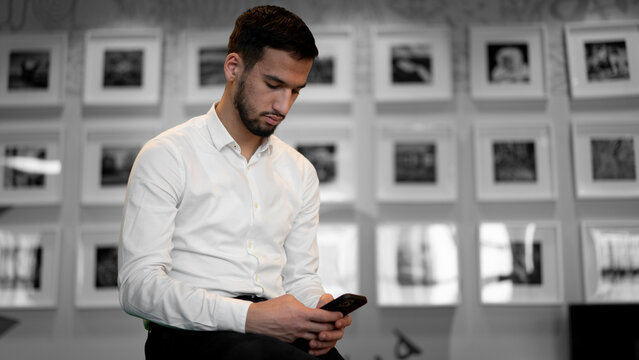 Checking Phone by Photo Wall