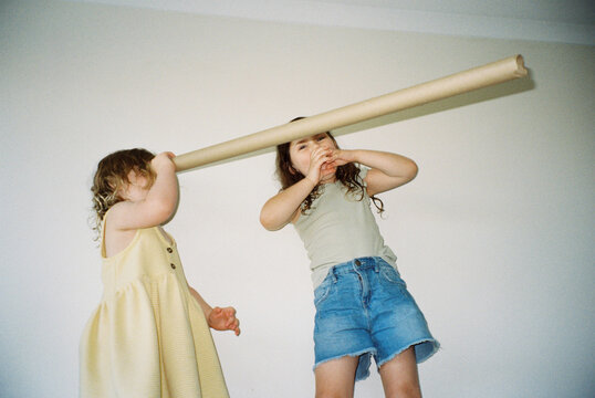 Two cheeky sisters standing on lounge playing imaginative games