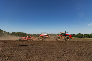 Fototapeta premium Modern tractor with seeding machine working on agricultural field