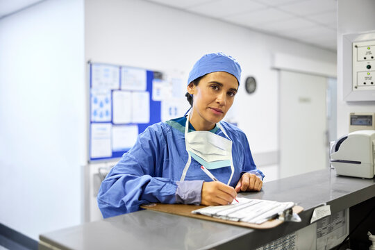 Exhausted Doctor Writing at Hospital Reception Desk