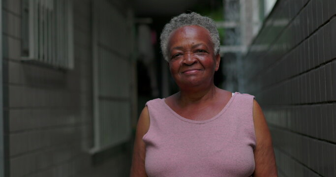 African American elderly woman outdoors standing in narrow passage smiling gently expressing resilience hope dignity life experience and calm spiritual confidence