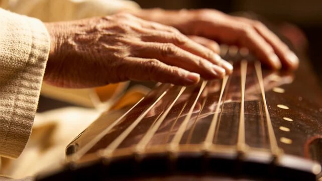 Plucking after fingers poised near bridge, musician hands making koto music for studio, light cuff