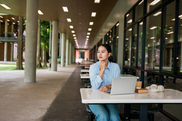 Fototapeta premium Young woman thinking, working remotely at university campus