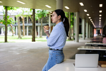 Fototapeta premium Young woman drinking coffee resting on campus