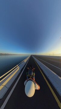 Vertical video. First Person Motorcycle Ride Along Southern Terminus of Bali Mandara Toll Road at Sunrise, Wide Angle Coastal Highway Above Calm Water and Golden Morning Light