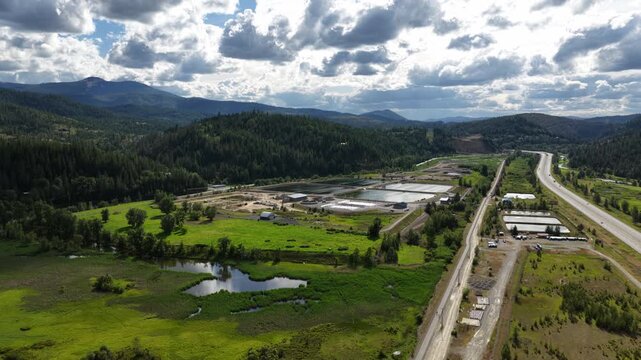 Aerial of industrial area with bodies of water in Smelterville Idaho along I90 with scattered buildings and rural landscape under cloudy skies