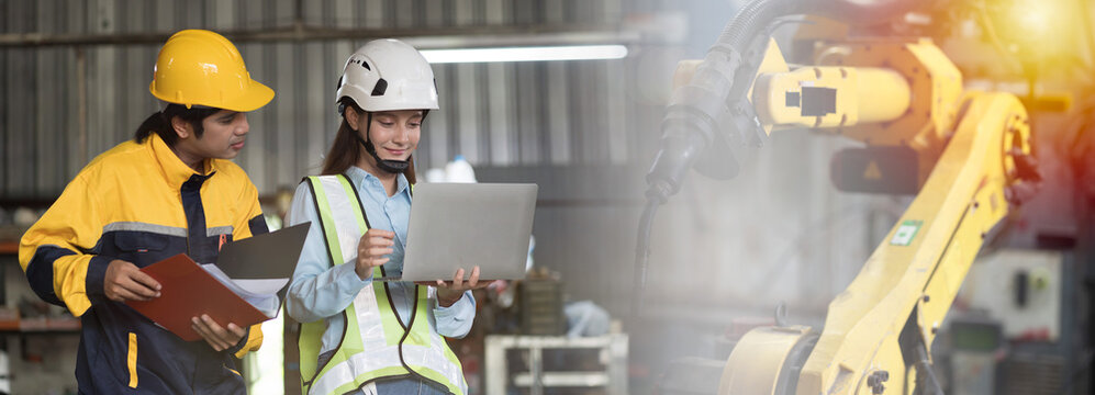 Industrial robotic arm welding for manufacturing. Engineer discussing work about maintenance, repair or parts replacement of robotic arm in workshop