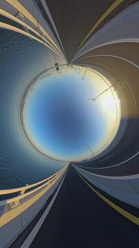 Vertical video. Planet Hole View of Southern Terminus of Bali Mandara Toll Road at Sunrise, Circular Highway Above Water Creating Abstract Geometric Travel Scene