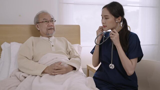 Professional attractive Asian woman nurse cardiologist using a stethoscope to examine a senior man patient for heart rate to analyze health problems in a hospital bed. Healthcare and medical concept. 