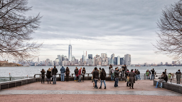 Tourists and visitors enjoying urban exploration and sightseeing at the waterfront with scenic views of the skyline, travel and tourism lifestyle, Liberty Island, New York City, USA.
