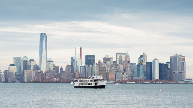 Tourism and travel ferry cruising the harbor past the Lower Manhattan skyline for sightseeing adventures in New York City, Manhattan, Lower Manhattan, Liberty Island, United States, USA.
