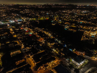 Obraz premium A UAV Drone view of Newport, California, near Corona Del Mar State Beach showing downtown and the lights of the city with the ocean dark below