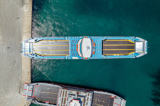 Ferry ship docked at port, transporting vehicles and passengers across turquoise sea