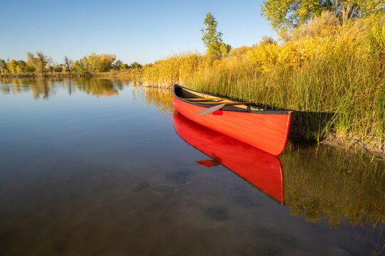 tandem canoe with a wooden paddle on a lake shore with fall scenery