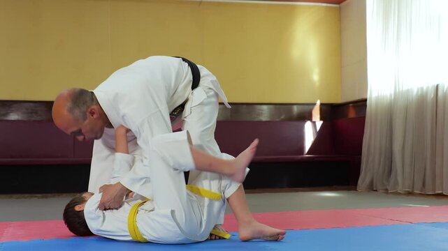 A coach teaches a young athlete to fall