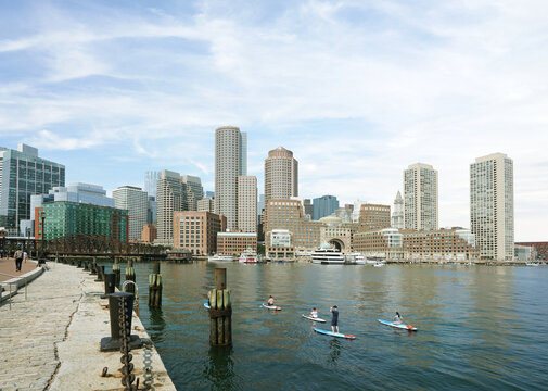 People paddleboarding with a view of downtown Boston skyline and harbor from the Harborwalk